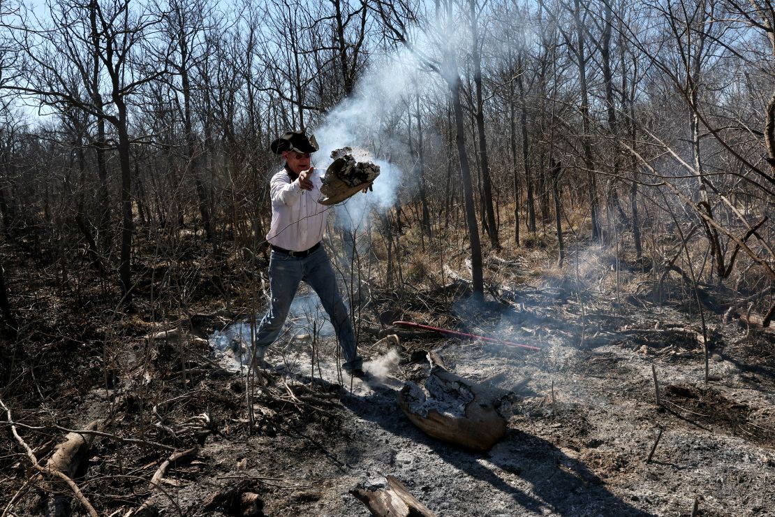 Sammy Schafer tosses a smoldering log into an area already burned after a massive wildfire ripped through the area near Canadian, Texas, on March 1, 2024.