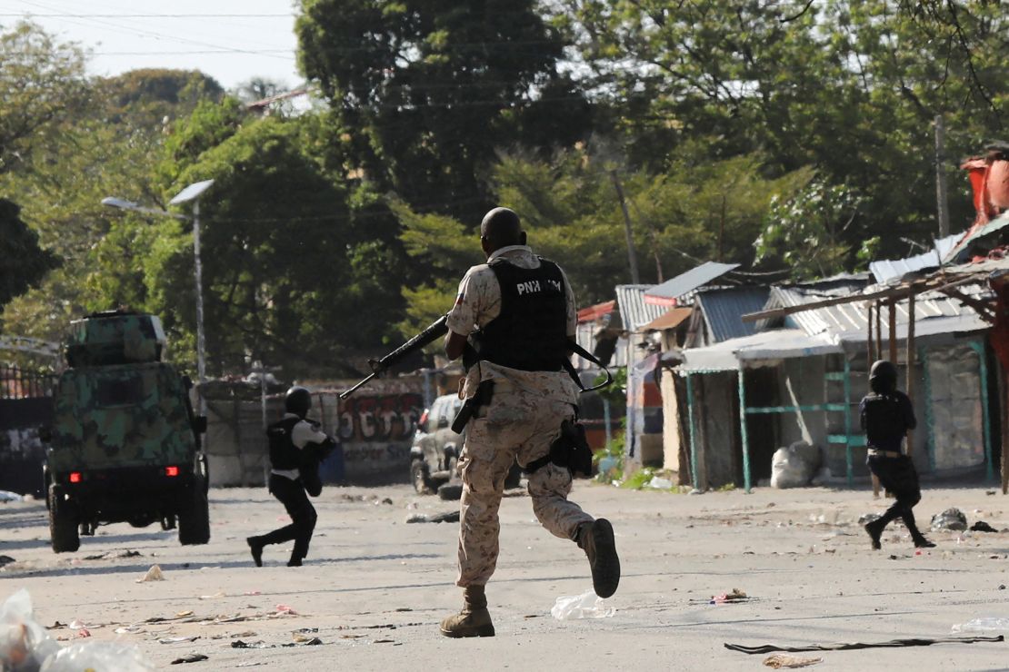 Police officers run holding their guns while confronting a gang in Port-au-Prince, Haiti March 1, 2024.