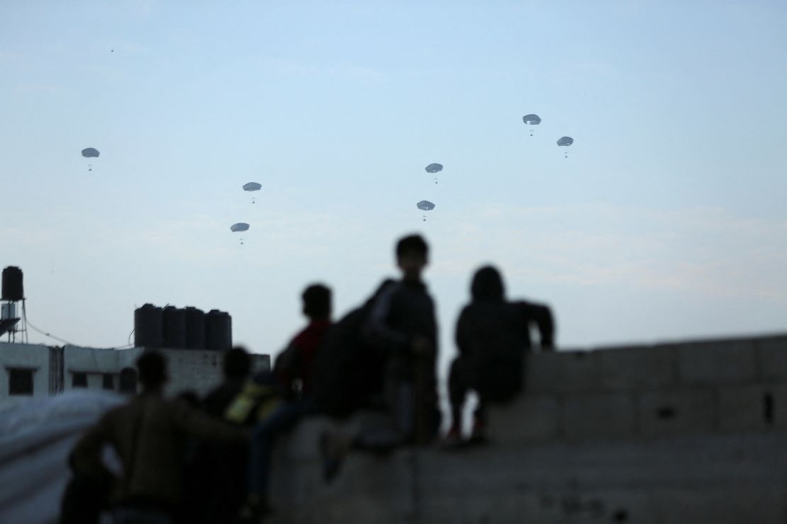 Palestinians watch as the US military carries out its first aid drop over Gaza City, in northern Gaza, on March 2. Human rights groups say the drops are a degrading way of getting aid to Gazans.