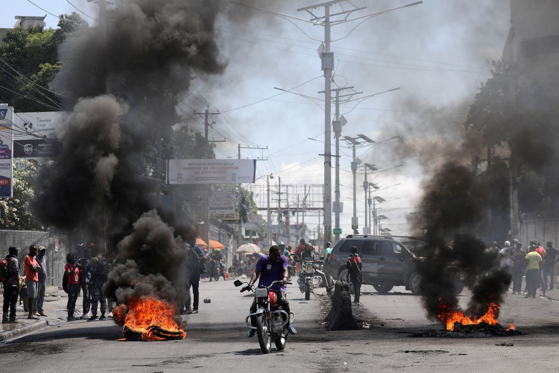 Motorists pass by a burning barricade during a protest in Port-au-Prince, Haiti, on March 7, 2024.