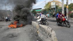 Motorists pass by a burning barricade during a protest as the government said it would extend a state of emergency for another month after an escalation in violence from gangs in Port-au-Prince, Haiti, March 7, 2024.