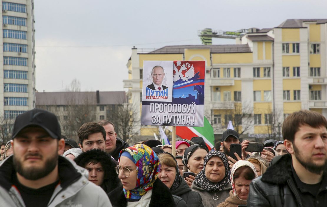 People take part in an election event in the Chechen capital Grozny, Russia. The slogan next to Putin on the poster reads: "Putin is always right! Vote for Putin!"