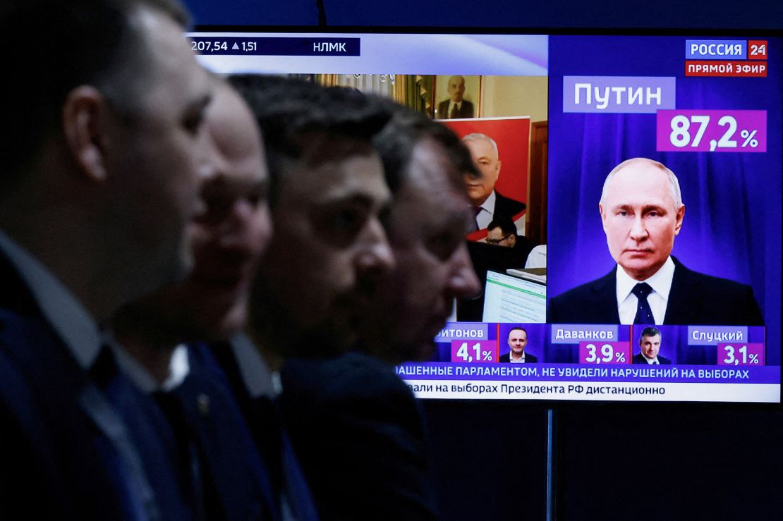 Men sit near a TV broadcasting news on results from the final day of the presidential election in Moscow, Russia, March 17, 2024.