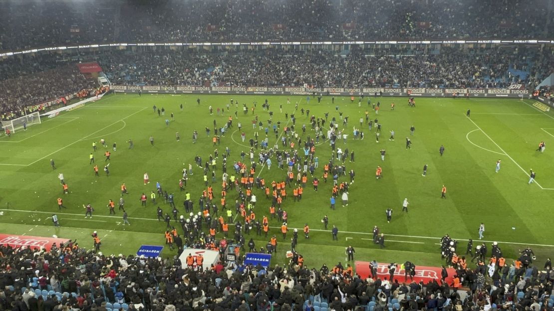 Trabzonspor fans invade the pitch and clash with Fenerbahçe players and security staff after the match.