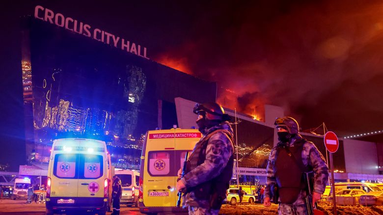 Law enforcement officers stand guard near the burning Crocus City Hall concert venue following a shooting incident, outside Moscow, Russia, March 22, 2024.