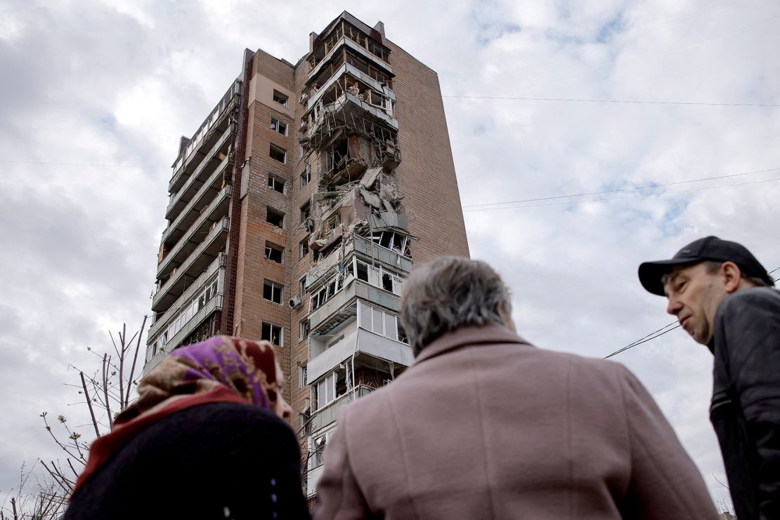 Local residents stand in a front of an apartment building hit by a Russian drone strike in Kharkiv, Ukraine in April.