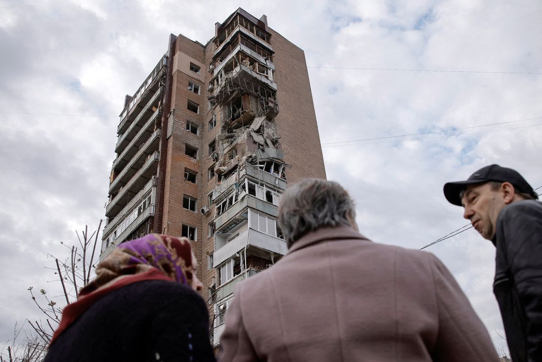 Local residents stand in a front of an apartment building hit by a Russian drone strike in Kharkiv, Ukraine, on April 4, 2024.