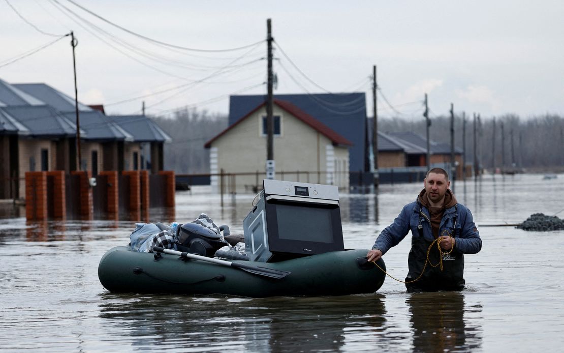 A man tows an inflatable boat holding his belongings along a flooded street in the Orenburg region.