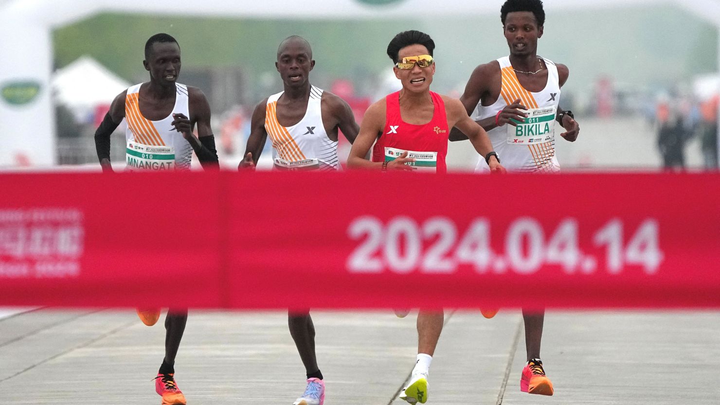 Chinese runner He Jie, Ethiopian Dejene Hailu Bikila and Kenyans Robert Keter and Willy Mnangat at the finish line of the Beijing Half Marathon on April 14, 2024.