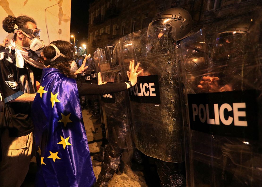 A protester draped in an European Union flag confronts riot police in Tbilisi, April 16, 2024.