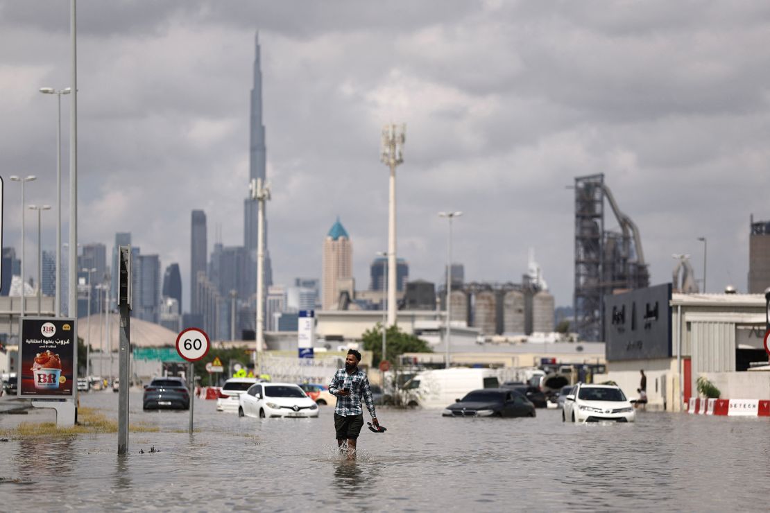 A man walks in flood water caused by heavy rains, with the Burj Khalifa tower visible in the background, in Dubai, United Arab Emirates, April 17, 2024. REUTERS/Amr Alfiky