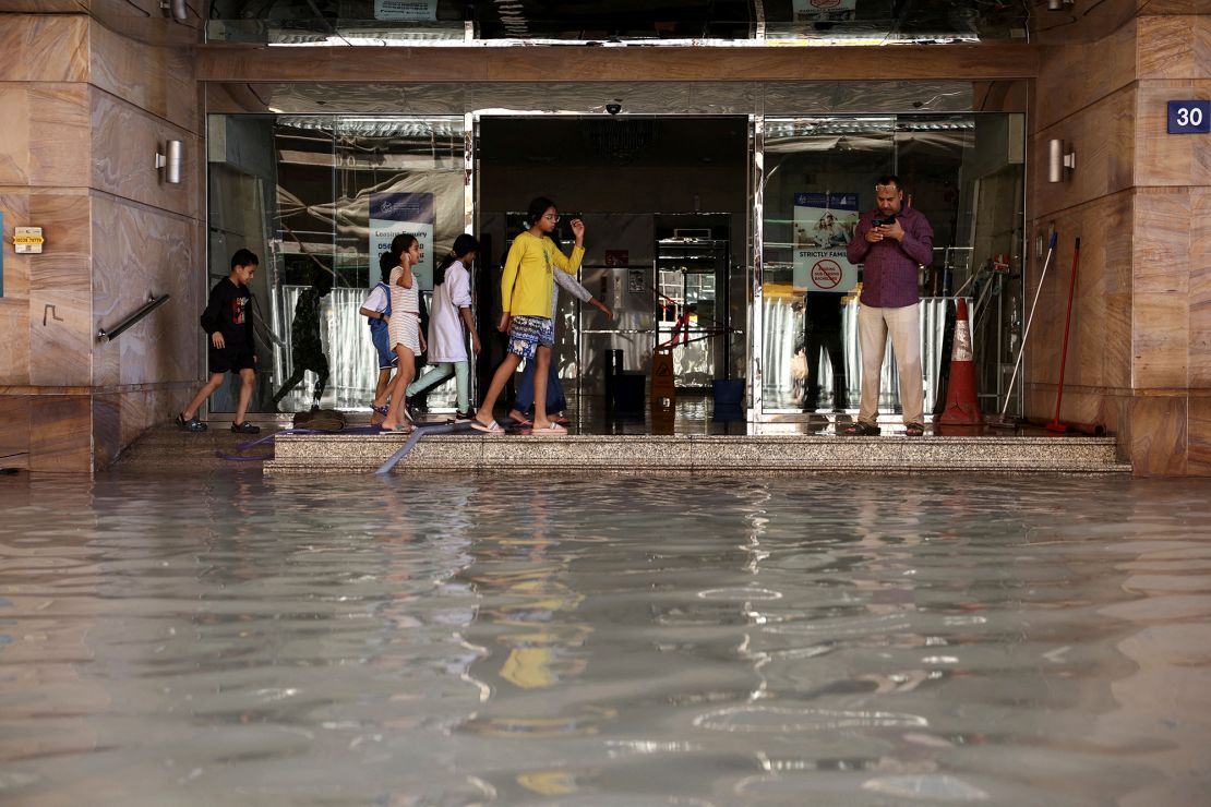 People stand as flood water caused by heavy rains covers the stairs of a residential building, in Dubai, United Arab Emirates on Wednesday.