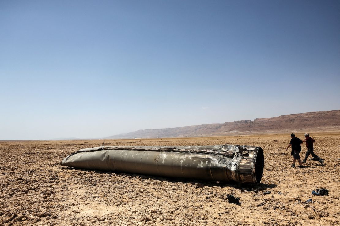 Orang-orang berjalan di samping sisa-sisa rudal balistik, di padang pasir dekat Laut Mati, setelah serangan rudal dan pesawat nirawak besar-besaran oleh Iran terhadap Israel, di Israel selatan pada 21 April 2024. REUTERS/Ronen Zvulun GAMBAR TPX HARI INI