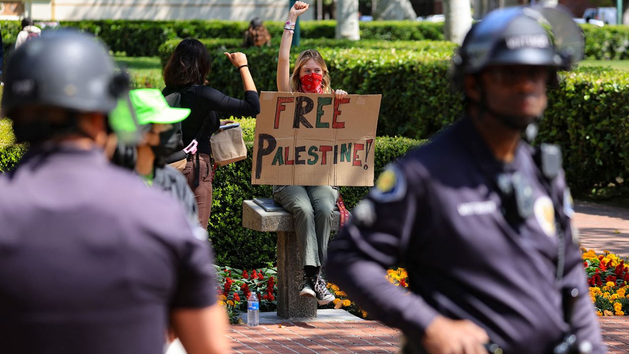 A demonstrator holding a sign holds up a fist after students built a protest encampment in support of Palestinians at the University of Southern California's (USC) Alumni Park, during the ongoing conflict between Israel and the Palestinian Islamist group Hamas, in Los Angeles, California, U.S., April 24, 2024. REUTERS/David Swanson