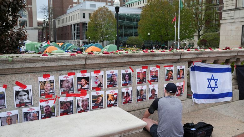 A person prays in front of photos of hostages posted on campus near an encampment where students are protesting in support of Palestinians at Columbia University, during the ongoing conflict between Israel and the Palestinian Islamist group Hamas, in New York City, New York, U.S., April 24, 2024.