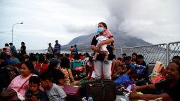 A woman carrying her child stands on the deck of KRI Kakap-881 warship, as people are being evacuated to North Minahasa Regency on Sulawesi island, following the eruptions of Mount Ruang volcano in Sitaro, North Sulawesi province, Indonesia, on May 1, 2024.