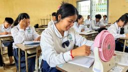 Student Lim Sokha, 15, uses a fan to cool down during her class in Phnom Penh, Cambodia, on May 2, 2024.