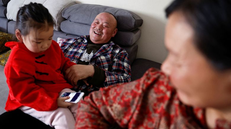 Wu Yonghou, 58, rests with his granddaughter sitting on his lap, next to his wife Yang Chengrong, 60, after a meal on Chinese Lunar New Year's Eve, at their apartment in a town bordering Beijing, in Hebei province, China February 9, 2024. REUTERS/Tingshu Wang