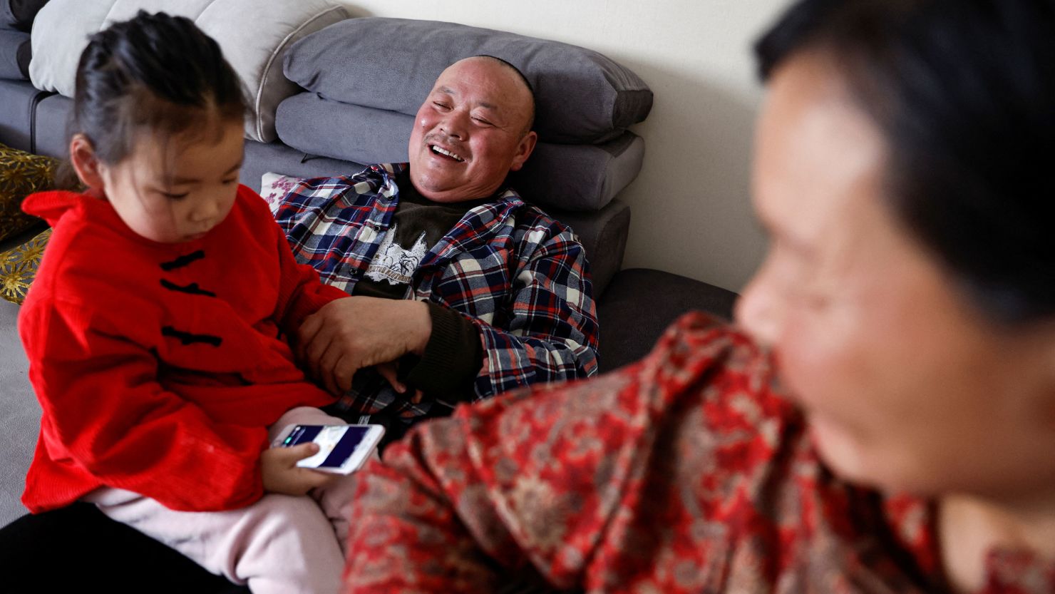 Wu Yonghou, 58, his wife Yang Chengrong, 60, and their granddaughter, relax after a meal at their apartment in a town in Hebei province February 9, 2024.