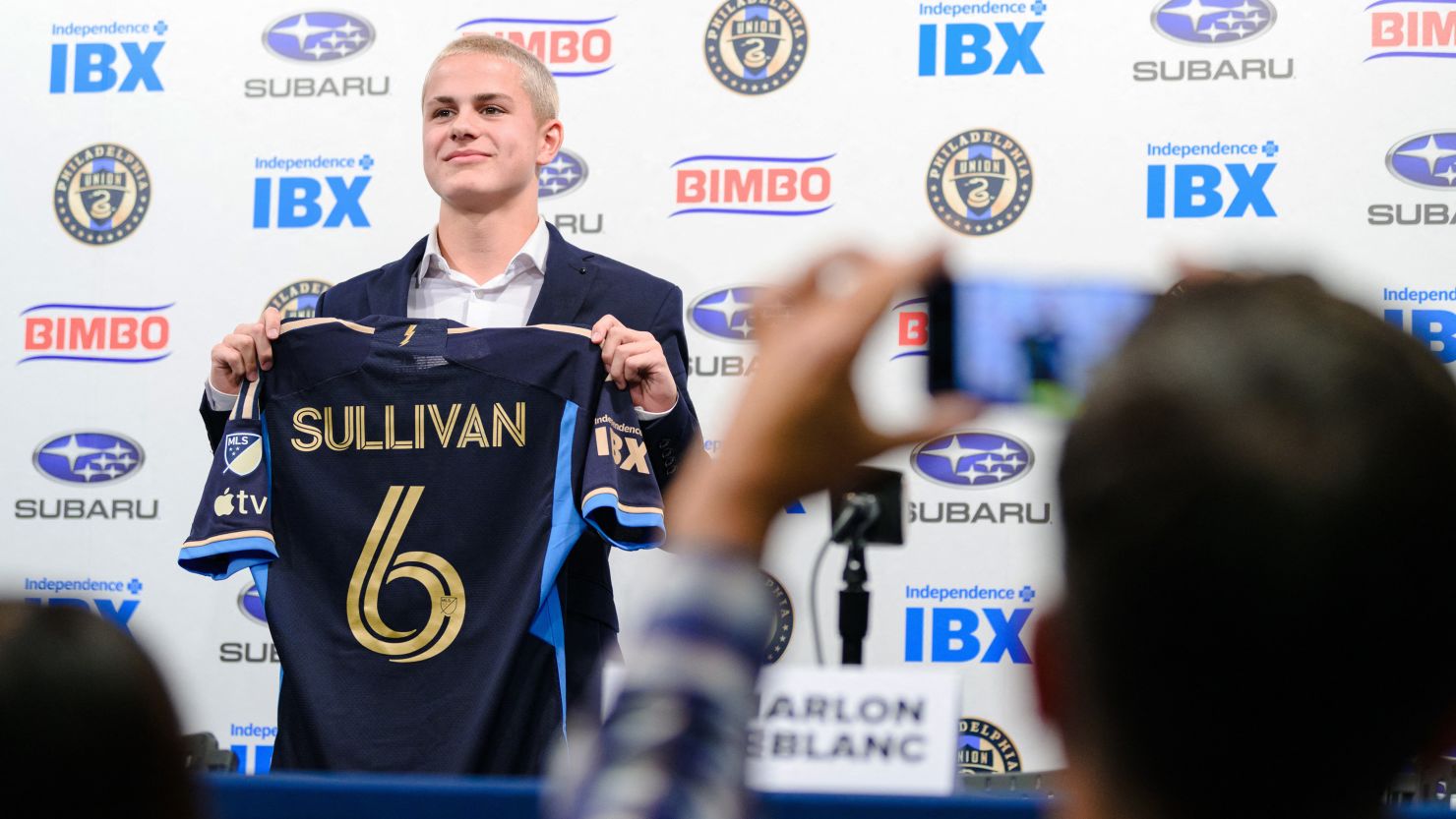 Cavan Sullivan poses with his jersey as his father, Brendan Sullivan, takes a photograph during the news conference announcing his professional contract at Subaru Park on Thursday, May 9, 2024.