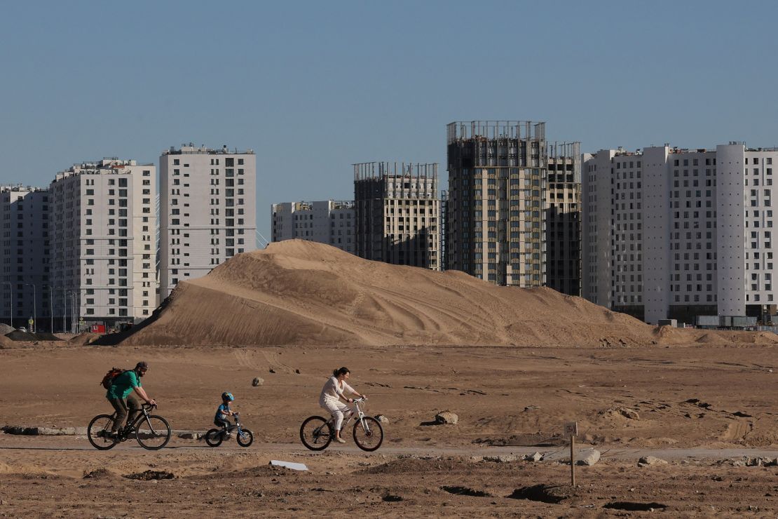 People ride bicycles along a temporary road, near apartment blocks under construction, in Saint Petersburg, Russia on May 18, 2024.