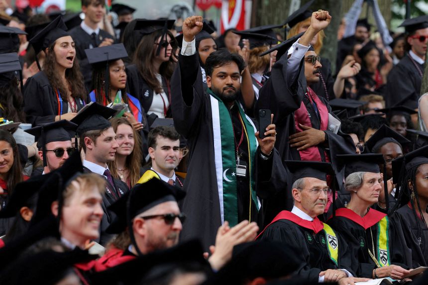 One of 13 students unable to graduate because they participated in pro-Palestinian protests raises his fist on May 23, 2024, during commencement exercises at Harvard.
