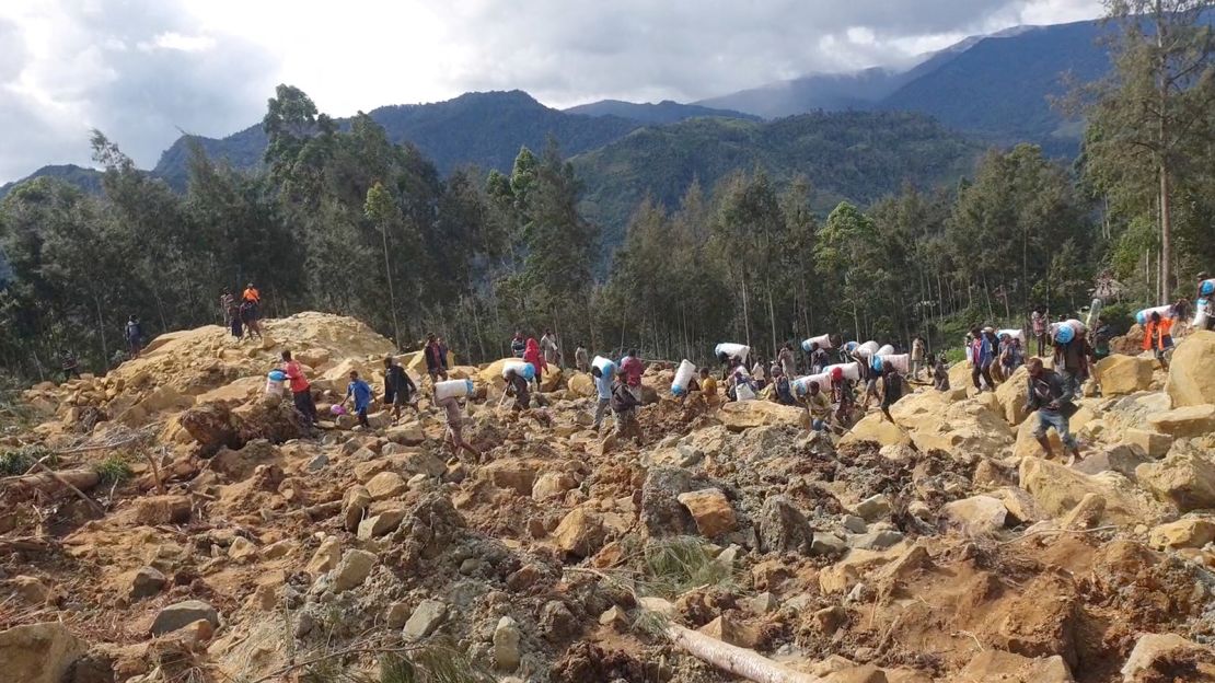 People carry bags in the aftermath of a landslide in Enga Province, Papua New Guinea, on May 24, 2024.