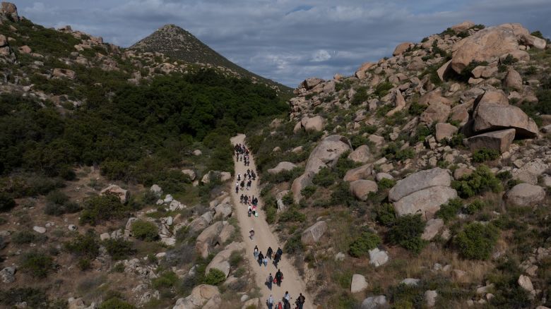 A drone view shows asylum seeking migrants from China and Turkey as they climb a hill while looking to surrender to immigration officials after crossing the border into the United States from Mexico in Jacumba Hot Springs, California, U.S., May 20, 2024.