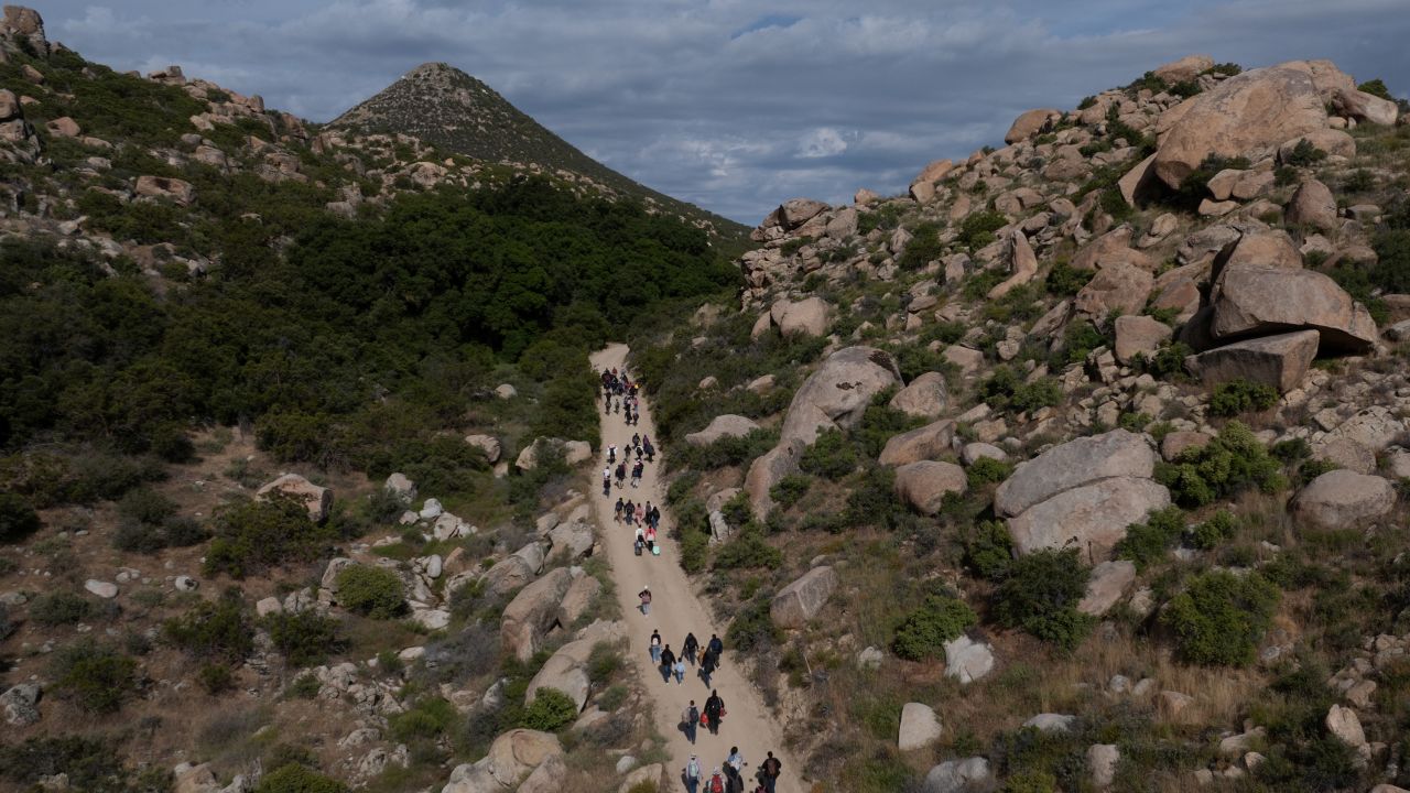 A drone view shows asylum seeking migrants from China and Turkey as they climb a hill while looking to surrender to immigration officials after crossing the border into the United States from Mexico in Jacumba Hot Springs, California, U.S., May 20, 2024.