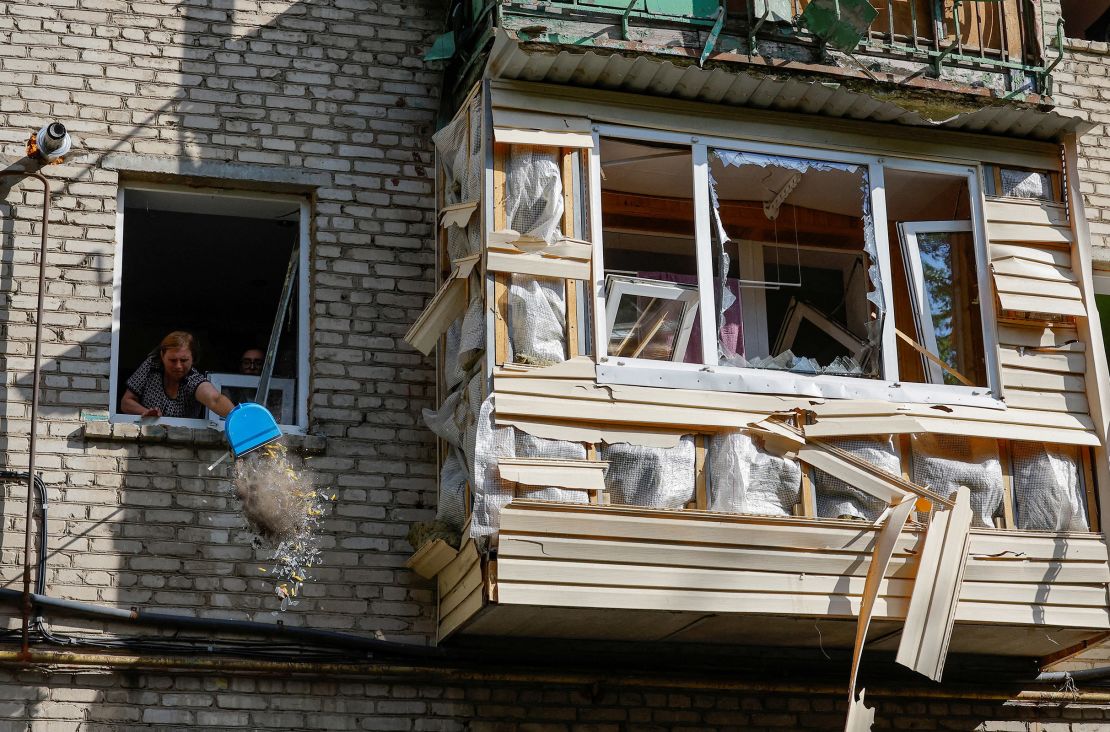 A woman cleans debris from an apartment.