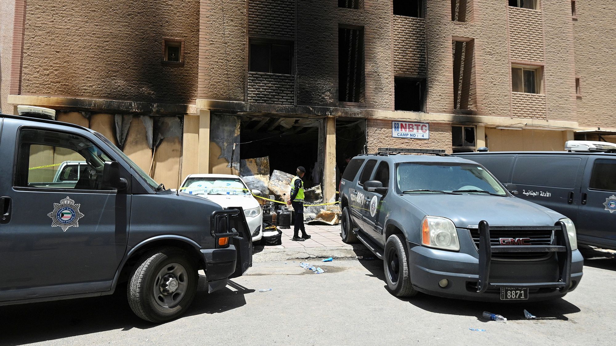 A Kuwaiti police officer is seen in front of a burnt building following a deadly fire, in Mangaf, southern Kuwait, June 12, 2024.