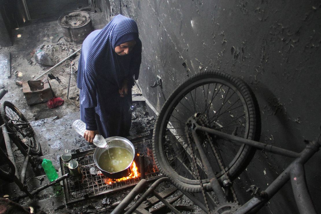 A displaced Palestinian woman uses water as she cooks in Jabalia refugee camp, northern Gaza.