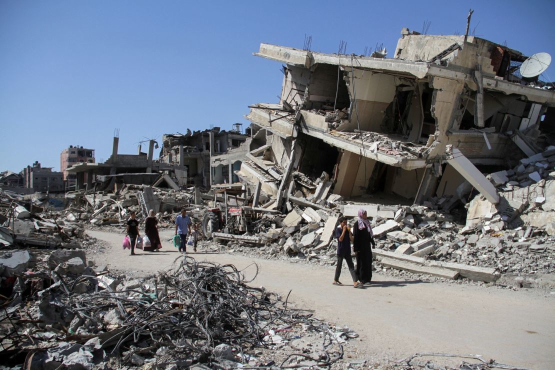 Palestinians walk among the debris of damaged buildings that were destroyed during an Israeli military attack in Beit Lahiya, northern Gaza Strip, June 12, 2024.