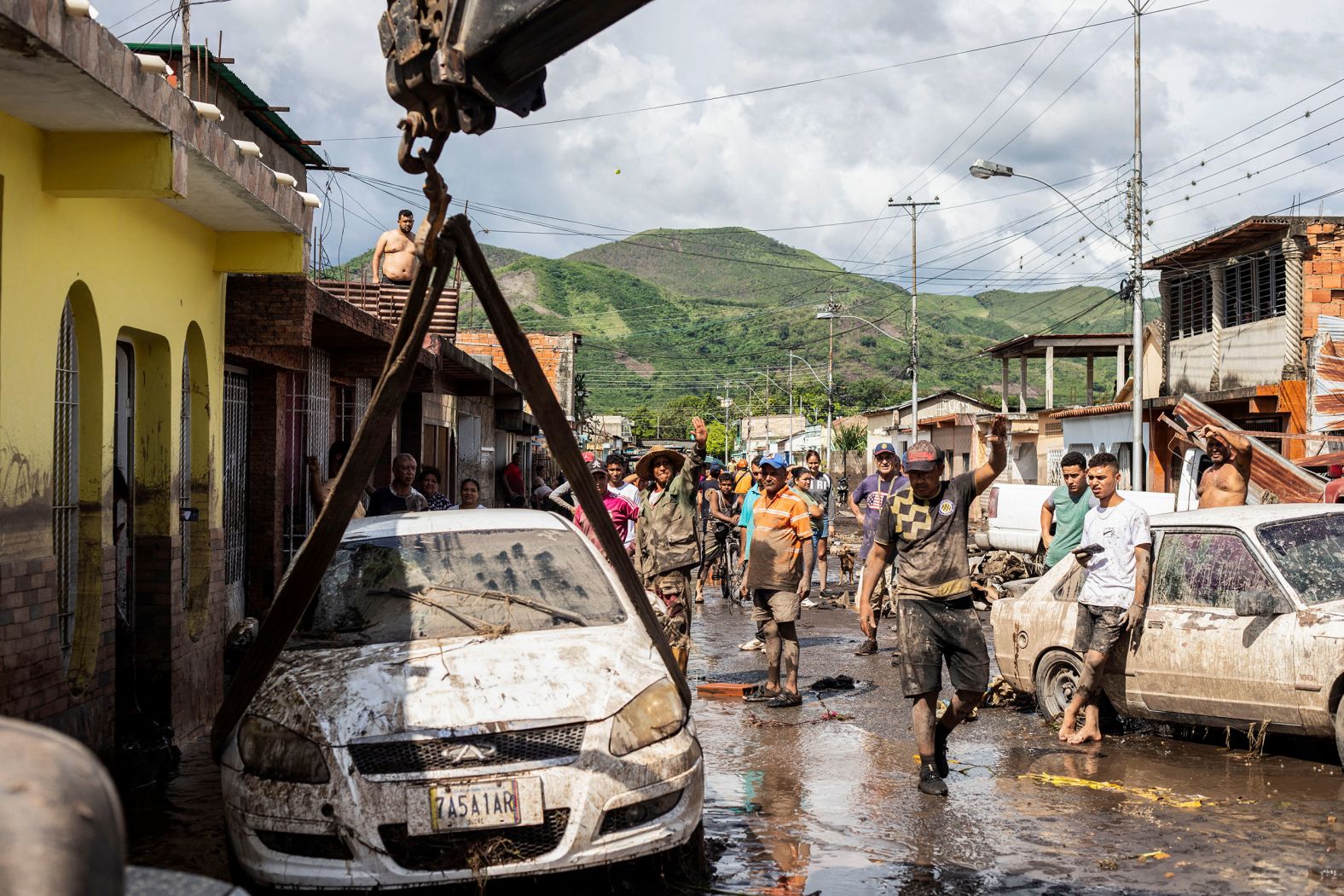 People walk near damaged vehicles in Cumanacoa, Venezuela, on July 2.