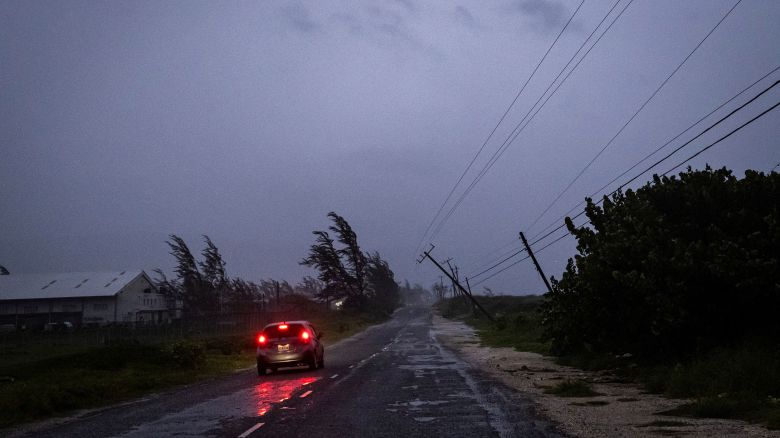 A car in the rain drives past a collapsed post as Hurricane Beryl hits the southern coast of the island, in Kingston, Jamaica, July 3, 2024. REUTERS/Marco Bello 