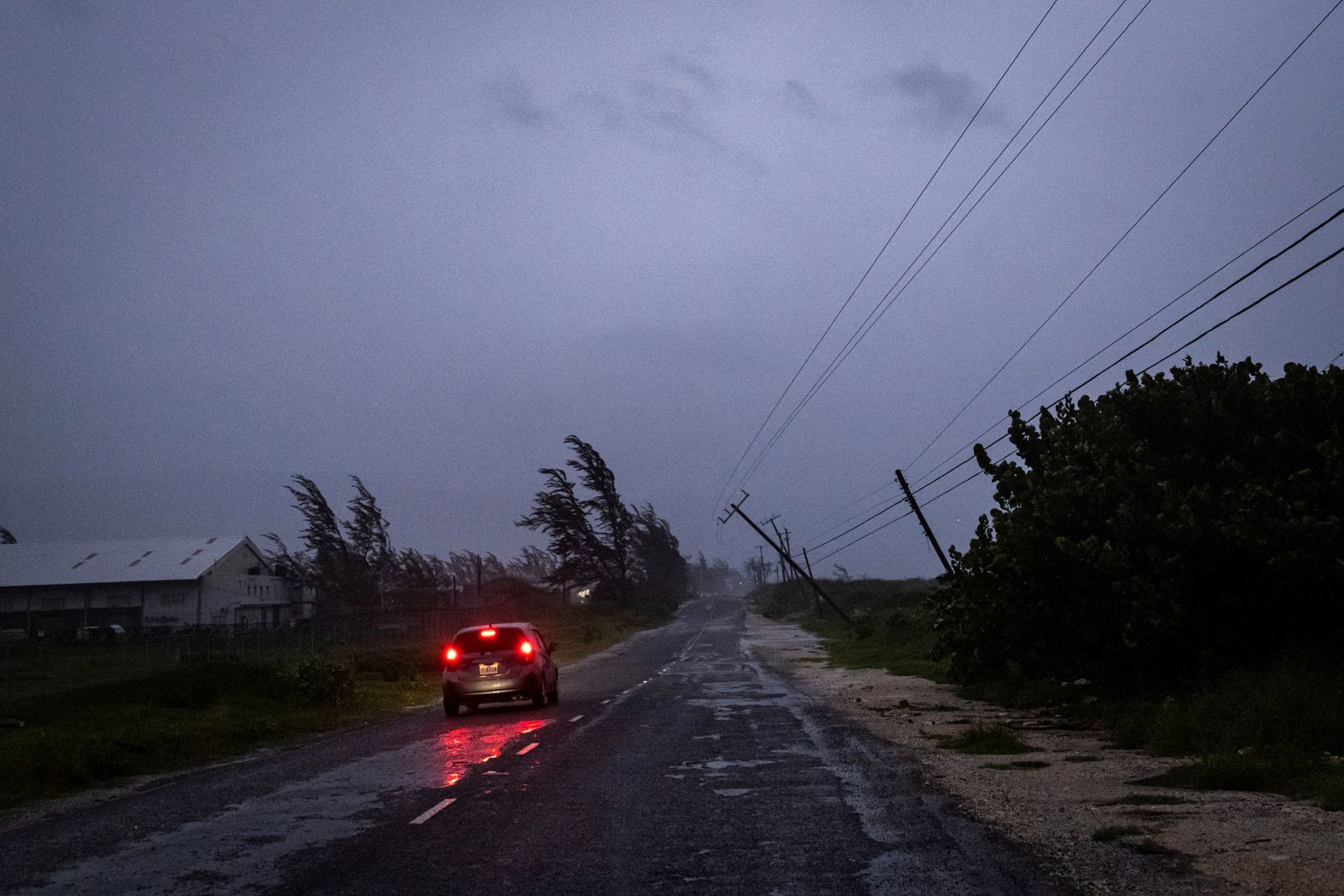 A car is driven near storm damage in Kingston on Wednesday.