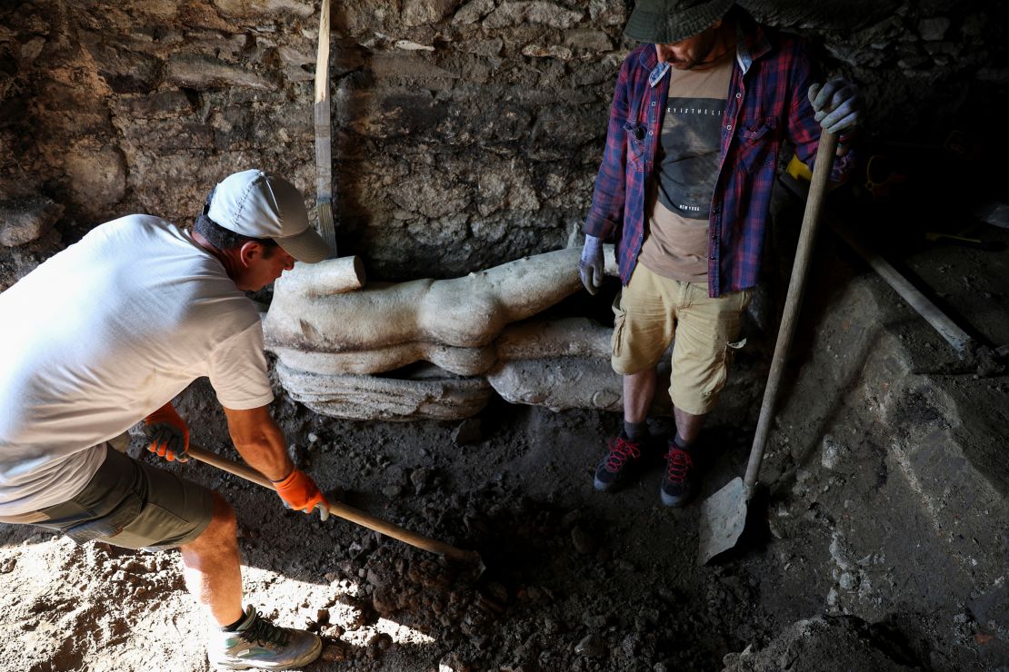 Archaeologists pictured with the statue, which was covered with soil in an ancient Roman sewer.