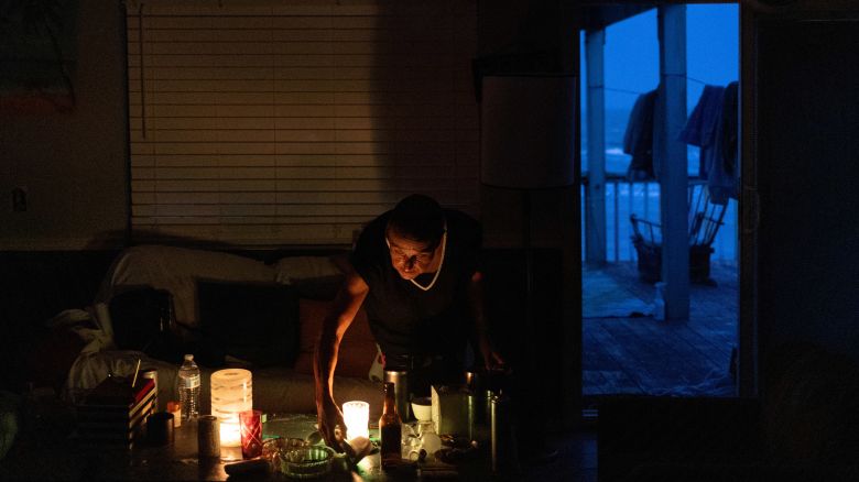 A man lights candles in his dark home.