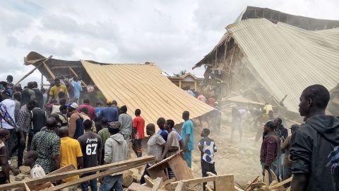 People stand near the rubble of a collapsed school building in Nigeria's Plateau state on Friday.