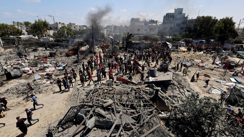 Palestinians gather near damage, following what Palestinians say was an Israeli strike at a tent camp in Al-Mawasi area on Saturday.