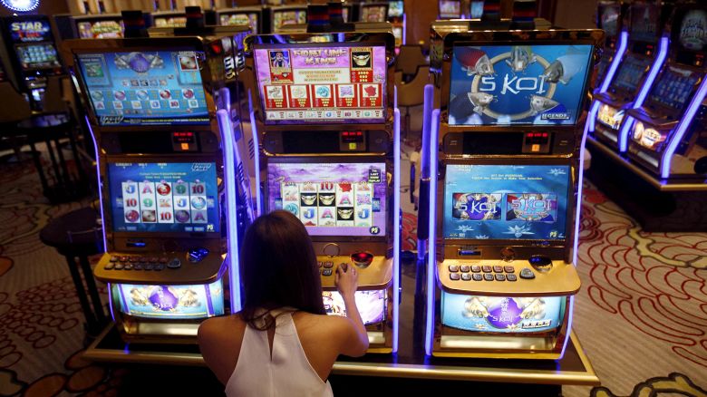 A casino trainee demonstrates how to play a slot machine in the Philippines, April 16, 2015.