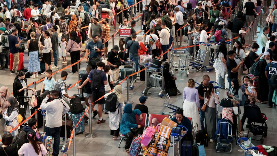 AirAsia passengers wait to be checked in manually at Kuala Lumpur International Airport after a global technology outage. - Hasnoor Hussain/Reuters