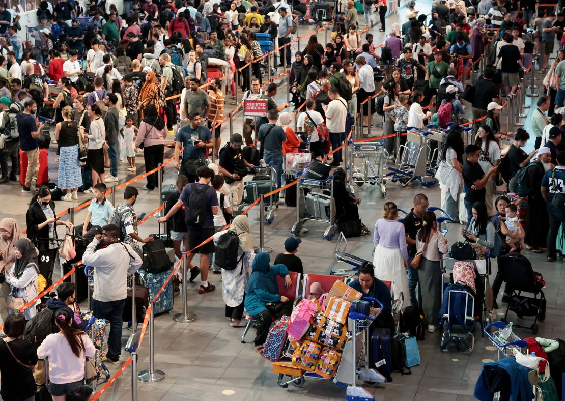 AirAsia passengers wait to be checked in manually at Kuala Lumpur International Airport after a global technology outage.