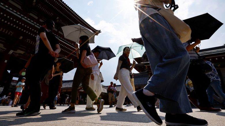 People shade themselves from the sun during extreme heat in Tokyo on Monday.