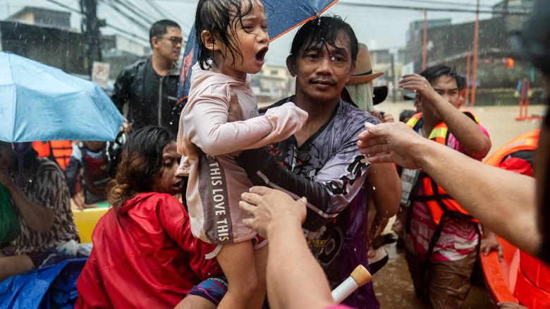 Rescuers assist a child getting off a boat along a flooded road following heavy rains brought by Typhoon Gaemi, in Marikina City, Metro Manila, Philippines, on July 24, 2024.