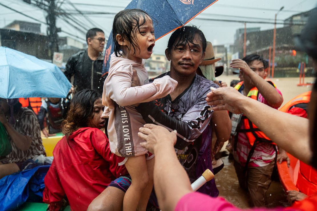 Rescuers assist a child getting off a boat along a flooded road following heavy rains brought by Typhoon Gaemi, in Marikina City, Metro Manila, Philippines, on July 24, 2024.