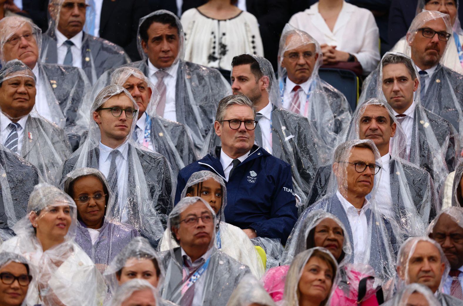 British Prime Minister Keir Starmer, at center in the blue jacket, watches the ceremony from the stands.