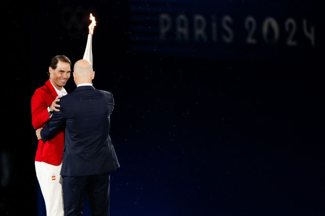 French soccer icon Zinedine Zidane, right, hands off the Olympic torch to Rafael Nadal, <a >the Spanish tennis star</a> who has won two Olympic gold medals and a record 14 French Opens. The torch passed to various athletes before ending up with Riner and Pérec.