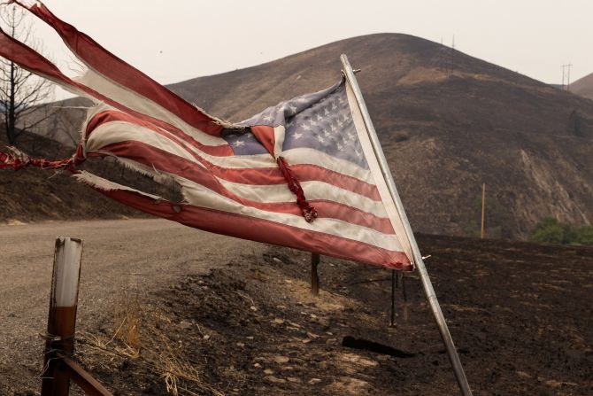 An American flag blows in the wind amid charred hillside from the Durkee Fire near Huntington, Oregon, on July 27, 2024.