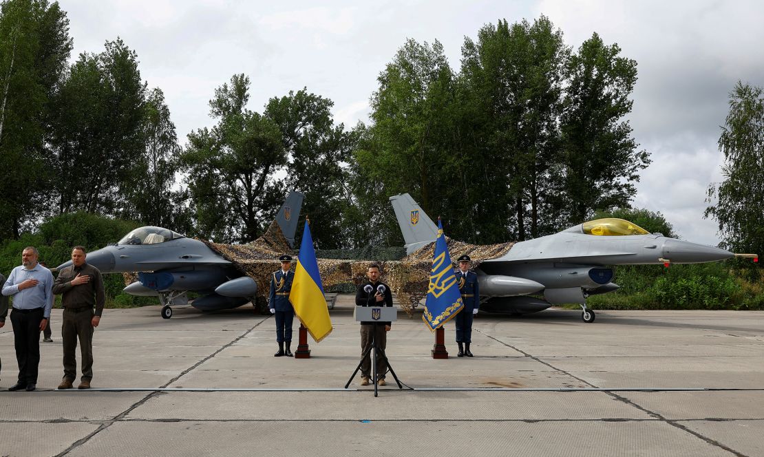 Ukraine's President Volodymyr Zelenskiy signs a national anthem next to F-16 fighting aircrafts during the Day of the Ukrainian Air Forces at an undisclosed location, Ukraine on August 4, 2024.